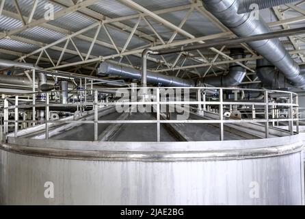 Behälter mit Geländer oben und angeschlossenem Rohr im Werk Stockfoto