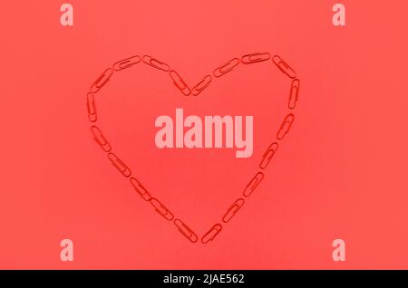 Herz aus Büroklammern auf rotem Hintergrund Stockfoto
