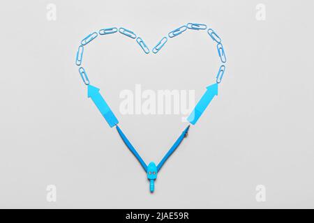 Herz aus blauen Büroklammern, Haftnotizen und Kompassen auf hellem Hintergrund Stockfoto