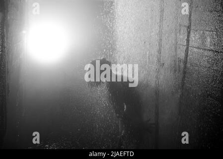 Junge Frau unter Wasserstrahlen in die Kanalisation. Stockfoto