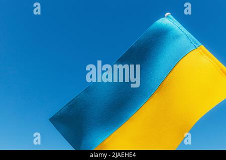 Große zweifarbige gelb-blaue ukrainische Staatsflagge, nationales Symbol flattert, winkt im Wind gegen den blauen Himmel an sonnigen Tagen. Kiew, Hauptstadt der Ukraine, Tag der Unabhängigkeitsverfassung, Nationalfeiertag Stockfoto