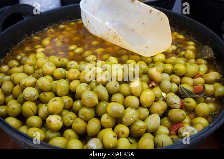 Zerkleinerte marinierte Oliven. Köstliche eingelegte Snack angezeigt Plastikkorb Stockfoto