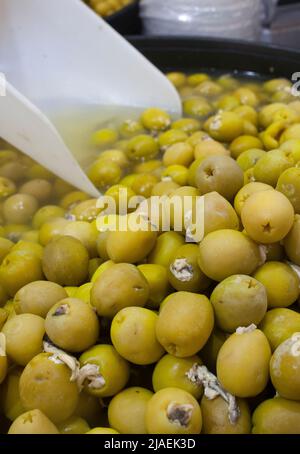 Eingelegte Oliven gefüllt mit Essig eingelegte Sardellen. Köstliche eingelegte Snack angezeigt Plastikkorb Stockfoto