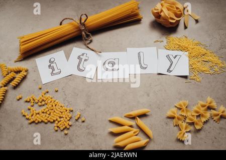 Schriftzug mit verschiedenen Nudelsorten und einer Handvoll Spaghetti auf dem Tisch Stockfoto