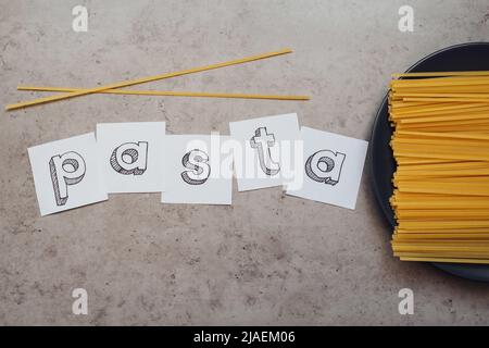 Schriftzug mit einer Handvoll Spaghetti auf dem Tisch Stockfoto