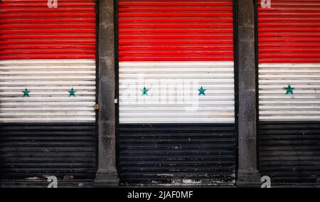 Damaskus, Syrien - Mai 2022: Syrische Flagge auf geschlossenen Fensterläden im leeren Markt (Suq Al Hamidiyah) während der Eid-Feiertage in Damaskus Stockfoto