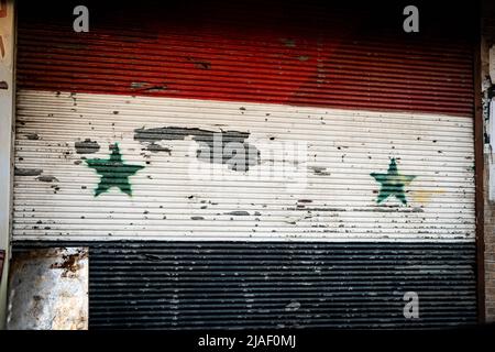 Damaskus, Syrien - Mai 2022: Syrische Nationalflagge auf verschlossenen Fensterläden gemalt Stockfoto