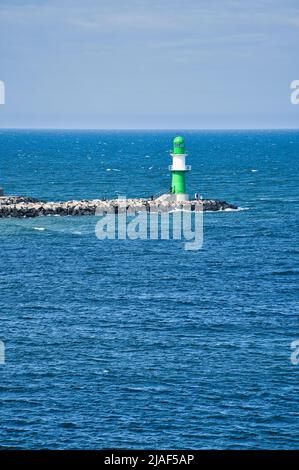 Grün-weißer Leuchtturm an der Warnow in Rostock an der Ostsee. Wahrzeichen der Stadt. Wellen am Steinrand. Landschaftsfoto aus Deutschland Stockfoto