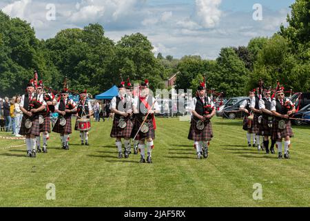 Die Leading Scottish Pipe Band marschiert in die Arena und unterhält Menschen bei einer Veranstaltung in Farnborough, Hampshire, England, Großbritannien Stockfoto