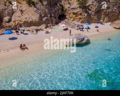 Golfo di Orosei Sardina, Blick von oben, atemberaubende Luftaufnahme eines Strandes voller Sonnenschirme und Menschen, die auf türkisfarbenem Wasser sonnenbaden und schwimmen. Cala Gonone, Sardinien, Italien, Cala Mariolu. Stockfoto