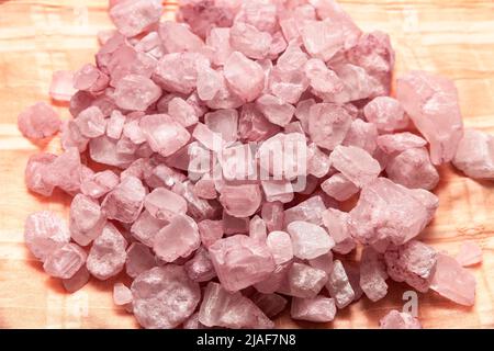 Haufen von Rosenquarzsteinen auf orangefarbenem Hintergrund Stockfoto