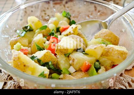 Hausgemachter Kartoffelsalat mit frischem Basilikum und roten Paprika. Veganer Kartoffelsalat mit einer Vinaigrette. Stockfoto