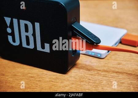 Ryazan, Russland - Januar, 15 2022: Tragbarer Audio-Lautsprecher JBL. Die Powerbank lädt tragbare Lautsprecher über ein USB-Kabel auf Stockfoto