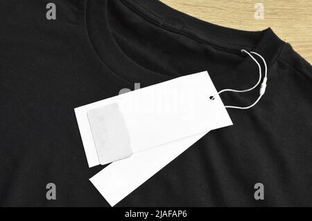 Schwarzes, sauberes blaues T-Shirt und leeres leeres Etikett auf Holzboden Stockfoto