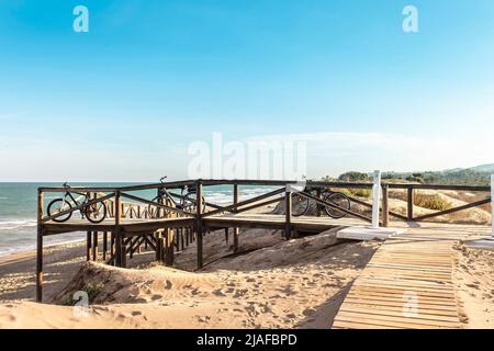 Drei Fahrräder auf einer Holzbrücke am Strand geparkt Stockfoto