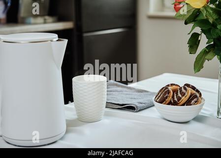 Teezeit, Wasserkocher mit gekochtem Wasser und Tasse für die Zubereitung von Tee auf dem Tisch, Frühstück am Morgen in der Küche Stockfoto