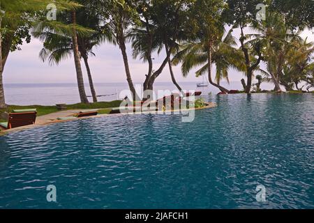 Swimmingpool eines Luxushotels am Lovina Beach mit Blick auf den Indischen Ozean, Indonesien, Bali Stockfoto