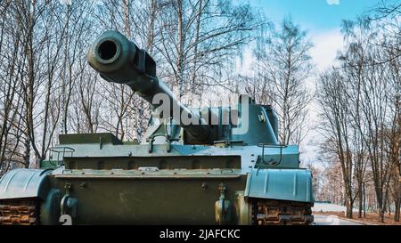 Das Fass einer Kanone einer russischen selbstfahrenden Haubitze vor dem Hintergrund von Bäumen und dem Himmel Stockfoto