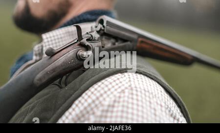 Nahaufnahme eines Mannes in traditioneller Schießkleidung mit Schrotflinte auf der Schulter. Stockfoto