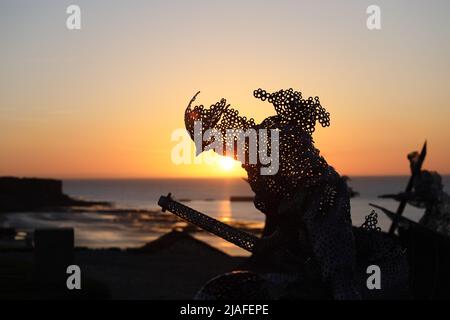 Lebensgroße skulpturale Figur im D-Day 75 Garden in Arromanches-les-Bains, Frankreich bei Sonnenuntergang. Die Installation wurde zuerst von John Everiss für erstellt Stockfoto