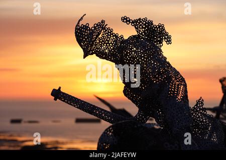 Lebensgroße skulpturale Figur im D-Day 75 Garden in Arromanches-les-Bains, Frankreich bei Sonnenuntergang. Die Installation wurde zuerst von John Everiss für erstellt Stockfoto