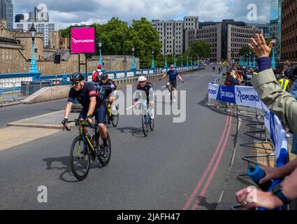 Eine Gruppe von Radfahrern, die am RideLondon 2022 teilnehmen, nähert sich der Ziellinie auf der Tower Bridge in London. Die Veranstaltung fand zum ersten Mal seit 2 statt Stockfoto