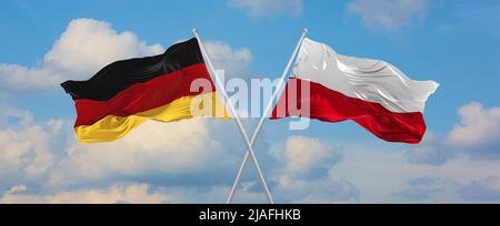 Zwei gekreuzte Flaggen Bundesrepublik Deutschland und Polen winken im Wind bei bewölktem Himmel. Konzept von Beziehung, Dialog, Reisen zwischen zwei Countri Stockfoto