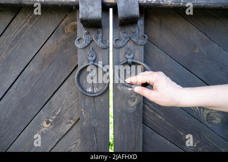 Die Hand der Frau öffnet das uralte Tor Stockfoto