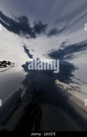 DAS UMGEKEHRTE AUGE: Ein kreativer Geist, der sich einer bedrohlichen Schurkensturmwolke am Abendhimmel nachstellt. Stockfoto