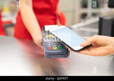 High-Angle-Nahaufnahme von nicht erkennbaren jungen Frau mit online Banking-Technologie auf dem Smartphone für Waren im Geschäft zu bezahlen Stockfoto