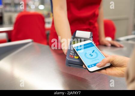 High-Angle-Nahaufnahme von nicht erkennbaren jungen Frau mit online Banking-Technologie auf dem Smartphone für Waren im Geschäft zu bezahlen Stockfoto