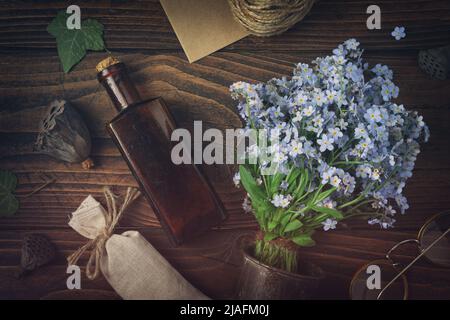 Tinktur oder Tränke Flasche, Beutel mit getrockneten Kräutern, Gläser, Bouquet von wilden Vergiss mich nicht Blumen. Draufsicht, flach liegend. Stockfoto