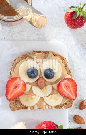 Kinder Frühstück Toast mit Erdnussbutter Aufstrich, Banane, Erdbeere Stockfoto