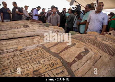 Saqqara, Ägypten. 30.. Mai 2022. Medienpersonal und Experten nehmen an einer Mediengelegenheit Teil, bei der eine neue archäologische Entdeckung von Artefakten aus der späten Zeit des alten Ägyptens (ca. 664 v. Chr. - 332 v. Chr.) auf dem heiligen Tierfriedhof in der Nekropole von Saqqara angekündigt wurde. Die Entdeckung umfasst 150 Bronzestatuen altägyptischer Gottheiten und insgesamt 250 hölzerne Sarkophage mit Mumien, die in einem guten Zustand erhalten sind. Quelle: Mahmoud El-Khawas/dpa/Alamy Live News Stockfoto