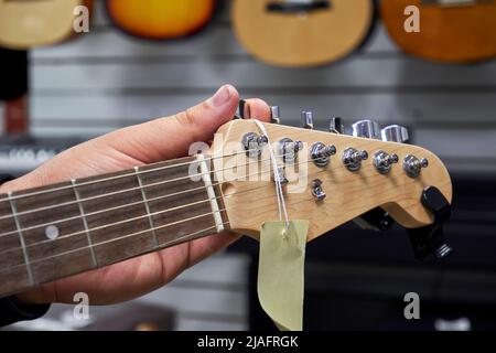 E-Gitarren-Tuning in einem Musikgeschäft. Nahaufnahme des Gitarrenkopfes Stockfoto