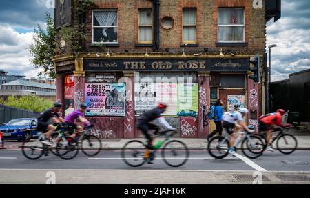 Eine Gruppe von Radfahrern, die an der RideLondon 2022 teilnehmen, passieren im East End von London einen verlassene Pub namens The Old Rose. Die Veranstaltung fand für die Fi statt Stockfoto