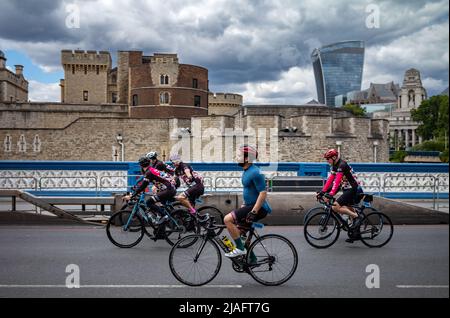 Eine Gruppe von Radfahrern, die am RideLondon 2022 teilnehmen, nähert sich der Ziellinie auf der Tower Bridge in London. Die Veranstaltung fand zum ersten Mal seit dem statt Stockfoto