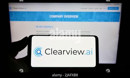 Person, die das Smartphone mit dem Logo des Gesichtserkennungsunternehmens Clearview AI Inc. Auf dem Bildschirm vor der Website hält. Konzentrieren Sie sich auf die Telefonanzeige. Stockfoto