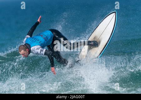 Ein männlicher Surfer, der an einem Surfwettbewerb im britischen Fistral in Newquay in Cornwall teilhat. Stockfoto