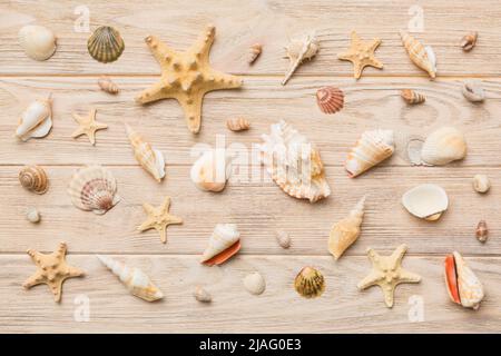 Summer Time Concept flache Lay-Komposition mit schönen Seesternen und Muscheln auf farbigem Tisch, Draufsicht. Stockfoto