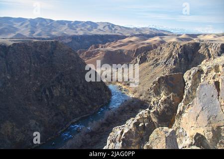 Charyn River in einer hohen Steinschlucht mit Blick auf Bergketten im Sommer bei sonnigem Wetter, Blick von oben Stockfoto