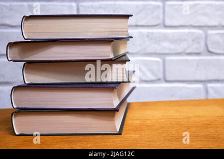 Stapel von Büchern Nahaufnahme auf Holztisch vor Wandhintergrund Stockfoto