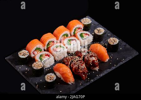Asiatische Küche. Sushi-Set aus Sashimi und Sushi-Rollen werden auf Steinschiefer serviert. Traditionelle Japanische Küche. Maki, Sashimi. Stockfoto
