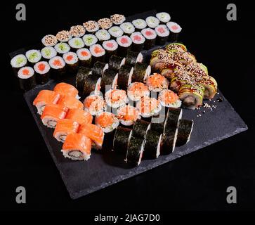 Verschiedene Arten von Sushi-Rollen mit Lachs, Gemüse, Fisch, Avocado, Kaviar und Sesam. Stockfoto