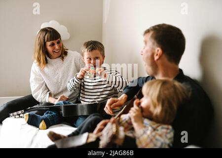 Eltern im Gespräch mit Sohn mit Down-Syndrom sitzen im Schlafzimmer zu Hause Stockfoto