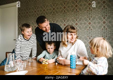 Lächelnde Eltern im Gespräch mit Tochter von Söhnen am Tisch Stockfoto