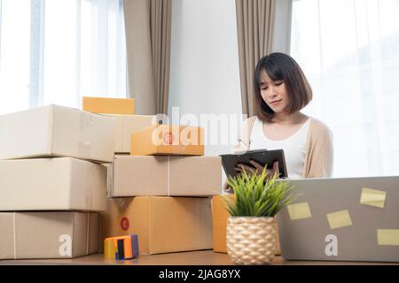Asiatische Frauen zählen Boxen vor dem Versand an Kunden, arbeiten von zu Hause aus, Kleinunternehmer oder Kleinunternehmer gerade erst anfangen worki Stockfoto