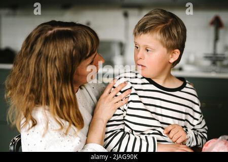 Mutter im Gespräch mit Sohn, der zu Hause ein Down-Syndrom hat Stockfoto