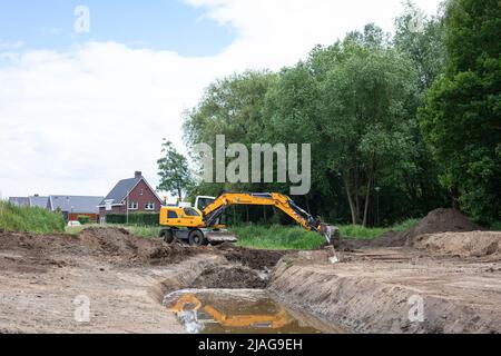 Bagger bei der Arbeit Wiederherstellung kanalisierten Streamlet wieder in mäandernde Form in einem Wohngebiet, Wasserwirtschaft in den Niederlanden Stockfoto