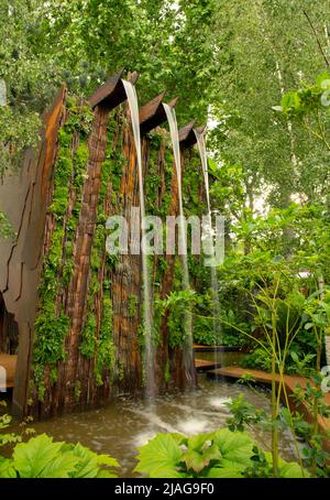 Ein Wasserfall über einer Klippe, umgeben von Grün, im Medite Smartply Building The Future Garden, entworfen von Sarah Eberle Stockfoto